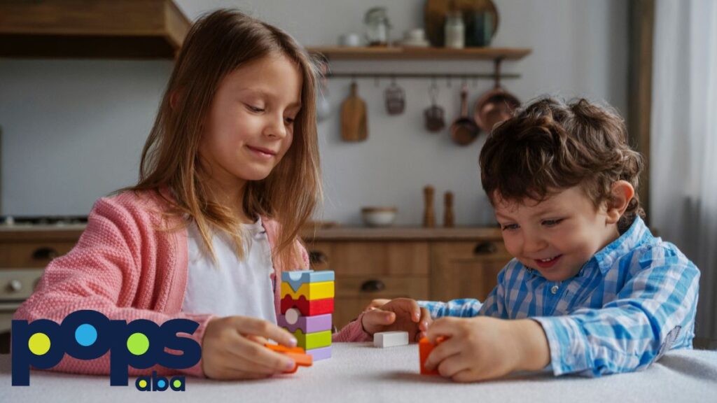 Two children, a boy and a girl, play with puzzle block pieces on a table in a brightly lit room, illustrating autism support levels.