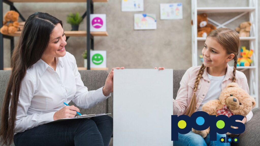 A therapist and a young girl sit on a sofa, holding up a plain white illustration board between them during a session related to ASD vs OCD.